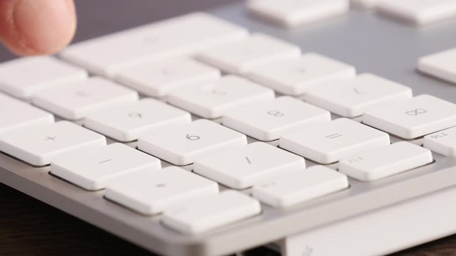 Extreme close-up of businessman typing numeric keypad on keyboard with finger.
