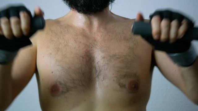 Close-up of naked hairy male chest working out on the rowing machine.