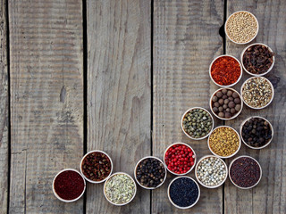 spices on a wooden background. Coriander, black pepper, paprika, mustard, turmeric, cumin, sumac, fenugreek, cloves, cubeb.