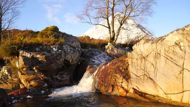 Well known waterfall on river Coupall at delta to river Etive. In background snowy cone of mountain Stob Dearg 1021 metres high. Higland in Scotland an marvelous sunny winter day. Dry grass.