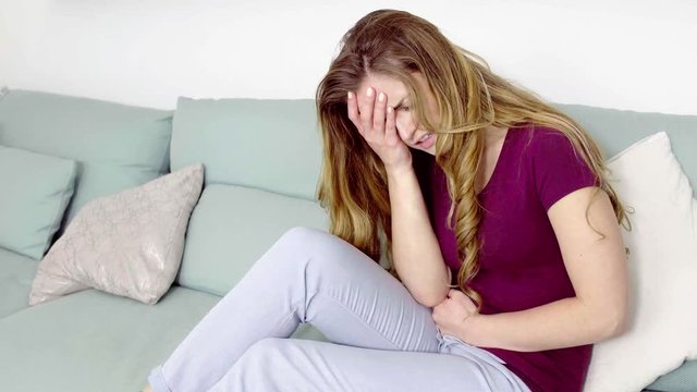 Woman in home with strong stomach menstruation pain