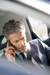Businessman talking on phone in taxi cab