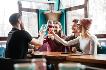 Smiling friends sitting in cafe and drinking alcohol.