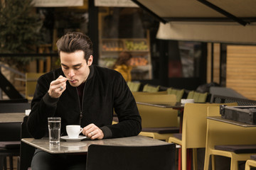 one young man sitting cafe tables coffee cup licking spoon