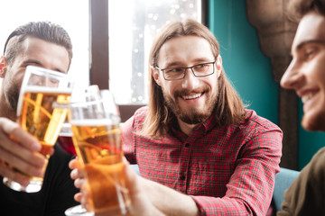 Young happy friends sitting in cafe while drinking alcohol.