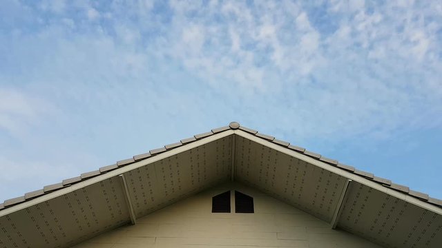 time lapse clouds in the sky with foreground of house roof