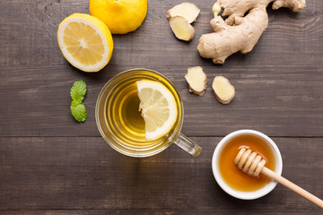 Cup of ginger tea with lemon, ginger, honey on wooden background