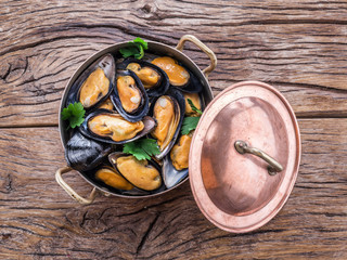 Mussels in copper pan on the wooden table.