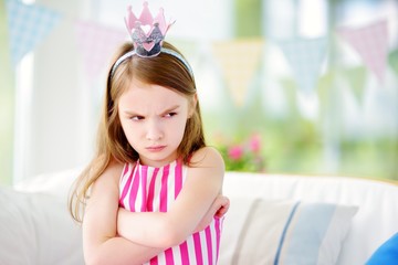 Moody little girl wearing princess tiara feeling angry and unsatisfied © MNStudio