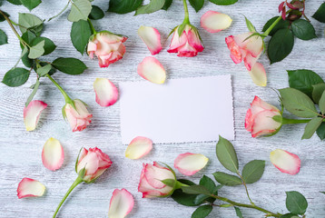 seven blossom rose and petals with a white card on the vintage wooden background