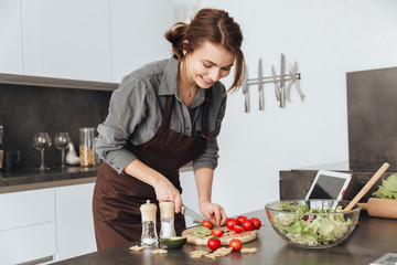 Pretty woman cooking in kitchen using tablet