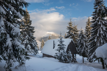 Magic winter landscape - the old wood hut, covered with snow