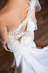 Bridesmaid makes bow-knot on the back of brides wedding dress