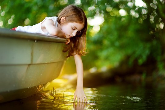Cute little girl having fun in a boat by a river