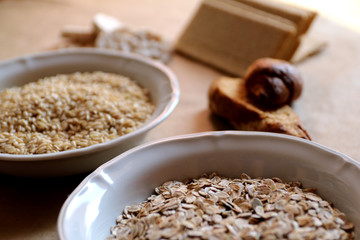 Oats and rice in a bowl close-up. Rice cakes and bread in background.