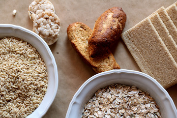 Oats and rice in a bowl. Rice cakes and bread in background. Food high in carbohydrates.