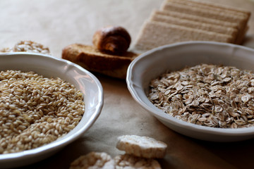 Oats and rice in a bowl. Rice cakes and bread in background. Food high in carbohydrates.