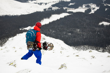 extreme free skier with safety helmet and avalanche backpack holding splitboard in cold winter mountains