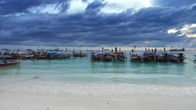 Long tail boats at the white sand beach on the storm clouds background, Koh Lipe, Thailand, 4k
