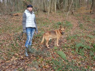 Young woman with dog walking in autumn forest