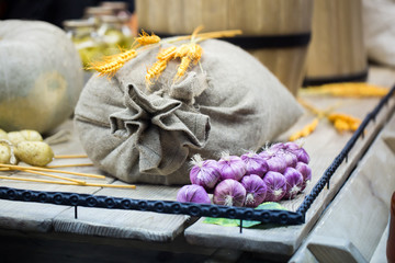 A bunch of onions near the bag and barrels on a wooden pallet