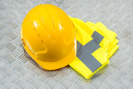Hard Hat and Folded Safety Vest on Steel Checker Plate