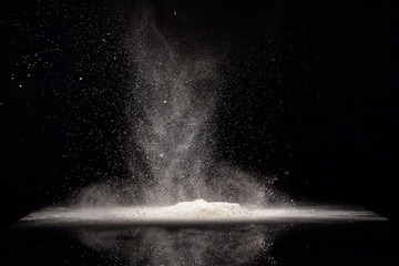 White flour falls on black glass cover