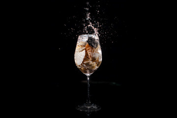 Sparkling wineglass with shells stands on black table