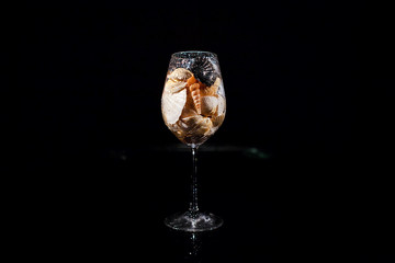 Sparkling wineglass with shells stands on black table