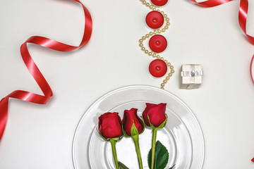 Fototapeta na wymiar Red Roses on a white plate, candles and giftbox. Romantic composition for Valentine's Day, Anniversary, Events. Place for text