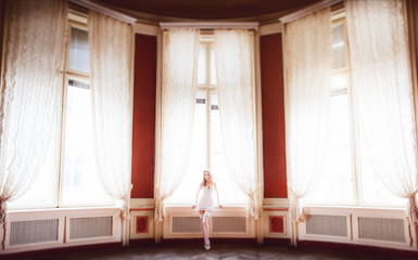 White curtains envelope seductive bride posing in lingerie before the window in red room