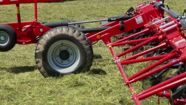 Rotary rakes are moving very fast when a farmer is preparing hay on a large field. He has a lot of work to do.
