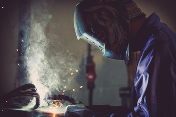 Industrial background of a man welding steel pipe generating sparks and gas - obrazy, fototapety, plakaty