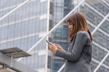 Business woman using a communication tool. The background is a building in the city.