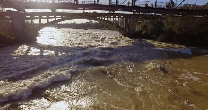 4k Aerial over American River during a flood in Northern California in 2017. People standing on a bridge watching.