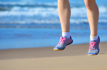 Fitness and running on beach, woman runner legs in shoes on sand near sea, healthy lifestyle and sport concept
