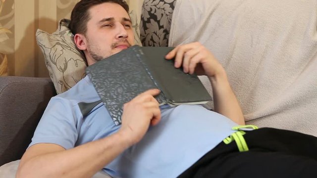 man reading a book lying on the couch and dreams