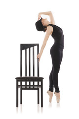 Pretty young ballerina posing with chair. Isolated on white
