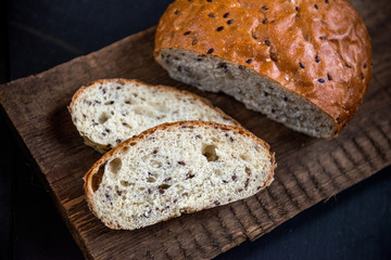 The whole grain bread with flax seeds, on slate and wooden background.