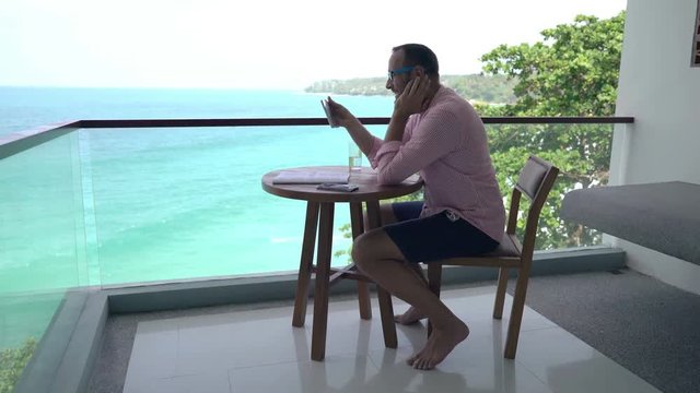 Young, happy man watching movie on tablet computer sitting on terrace 
