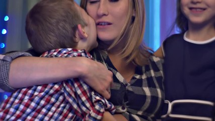 Happy Mom Hugs Kisses His Son and Daughter Tenderly Family Celebrates Christmas Holidays at Home Pregnant Mom and Two Her Children Roses Made of Fabric