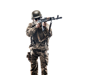 Studio shot of young serviceman in uniform holding machine gun and aiming on white background. Isolate.