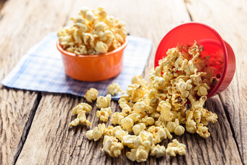 Sweet caramel popcorn in a bowl on blue cotton napkin against wooden background