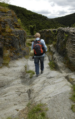 eine frau mit rucksack wandert zwischen mauern auf der felsigen zufahrt zur schmidtburg