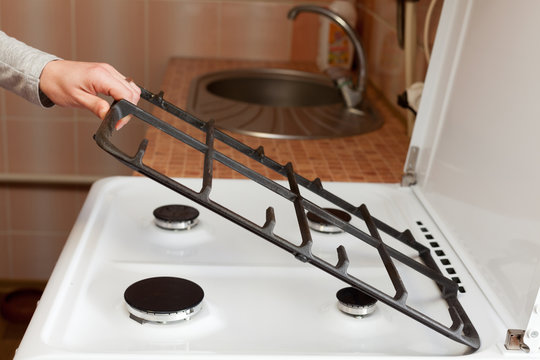 Housewife hold metal grates to clean the dirty kitchen gas stove