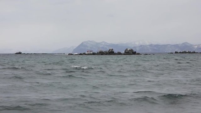 冬の噴火湾　岩礁の中を走る漁船