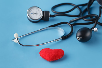 Heart healthcare concept, thonometer and toy heart on blue background