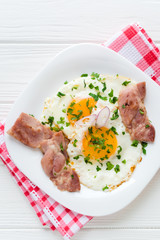 Fried eggs with bacon on white background