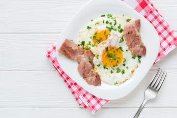 Fried eggs with bacon on white background
