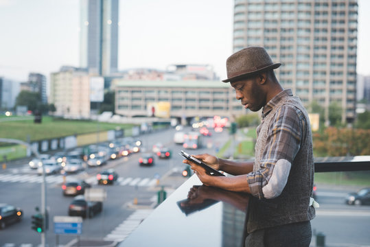 young handsome afro black man sitting on a handrail outdoorusing smart phone - technology, social network, communication concept